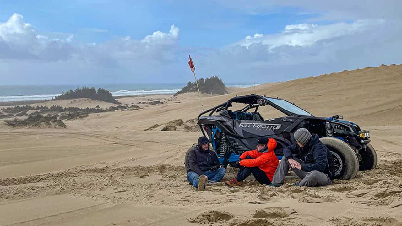 A group of guys enjoying the beach while taking refuge from the wind in Winchester, Oregon.